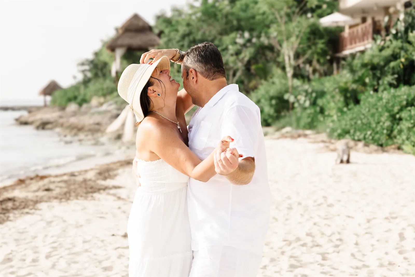 A happy couple laughing and dancing together on the beach during a vacation photo session at Dreams Natura.
