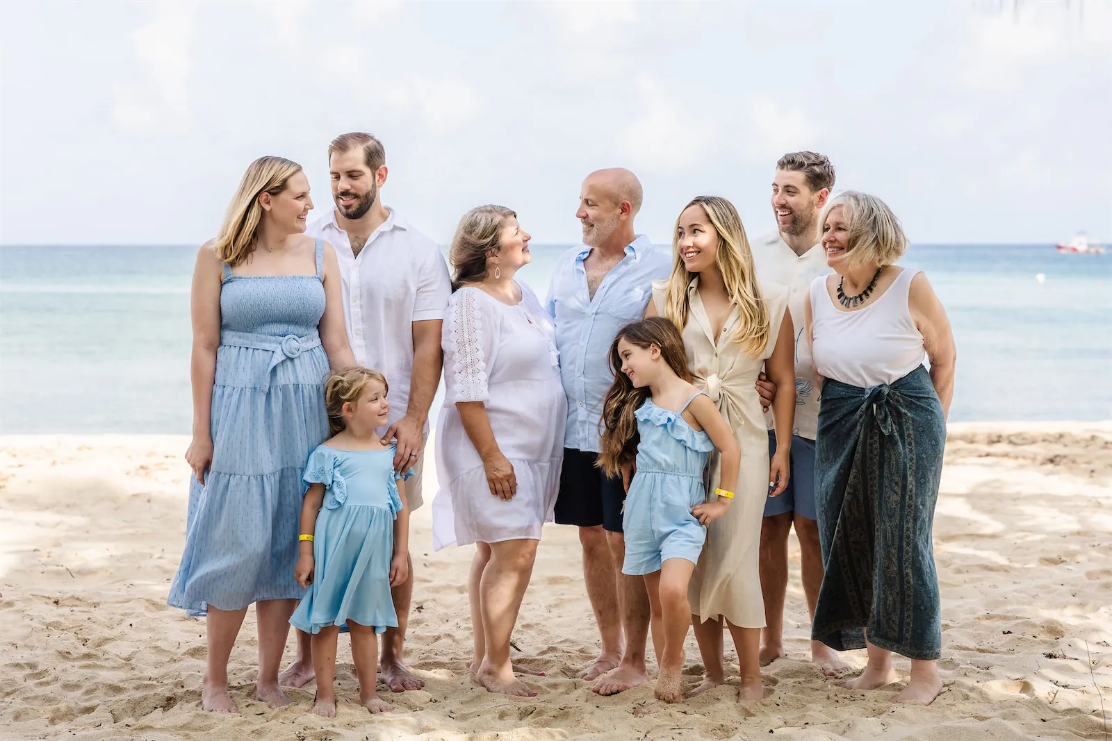 A large multigenerational family posing for a vacation portrait on the sand at Paradise Beach in Cozumel, Mexico.
