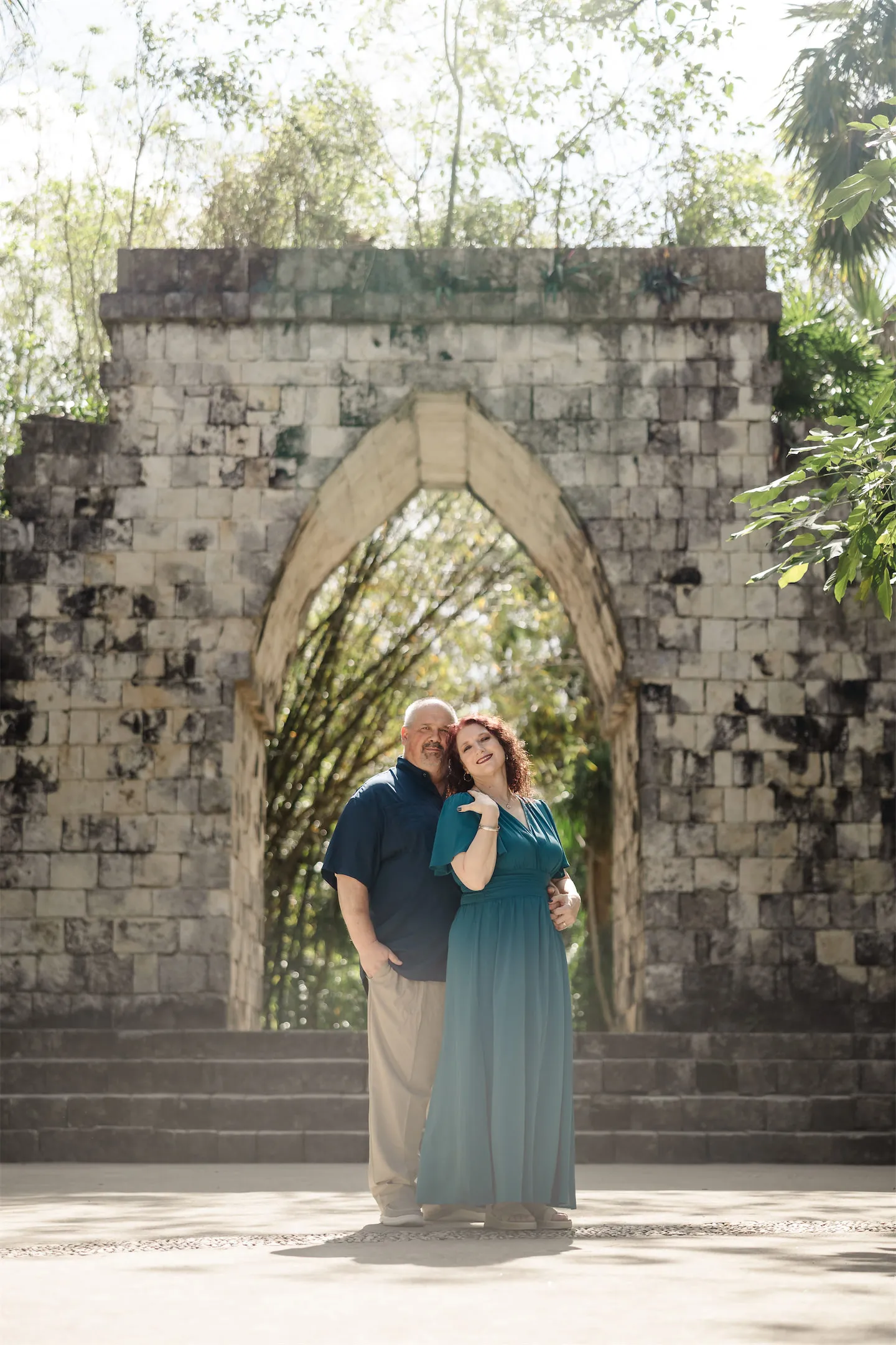 A couple posing in front of a historic Mayan stone archway in the tropical gardens of Chankanaab Park, Cozumel.