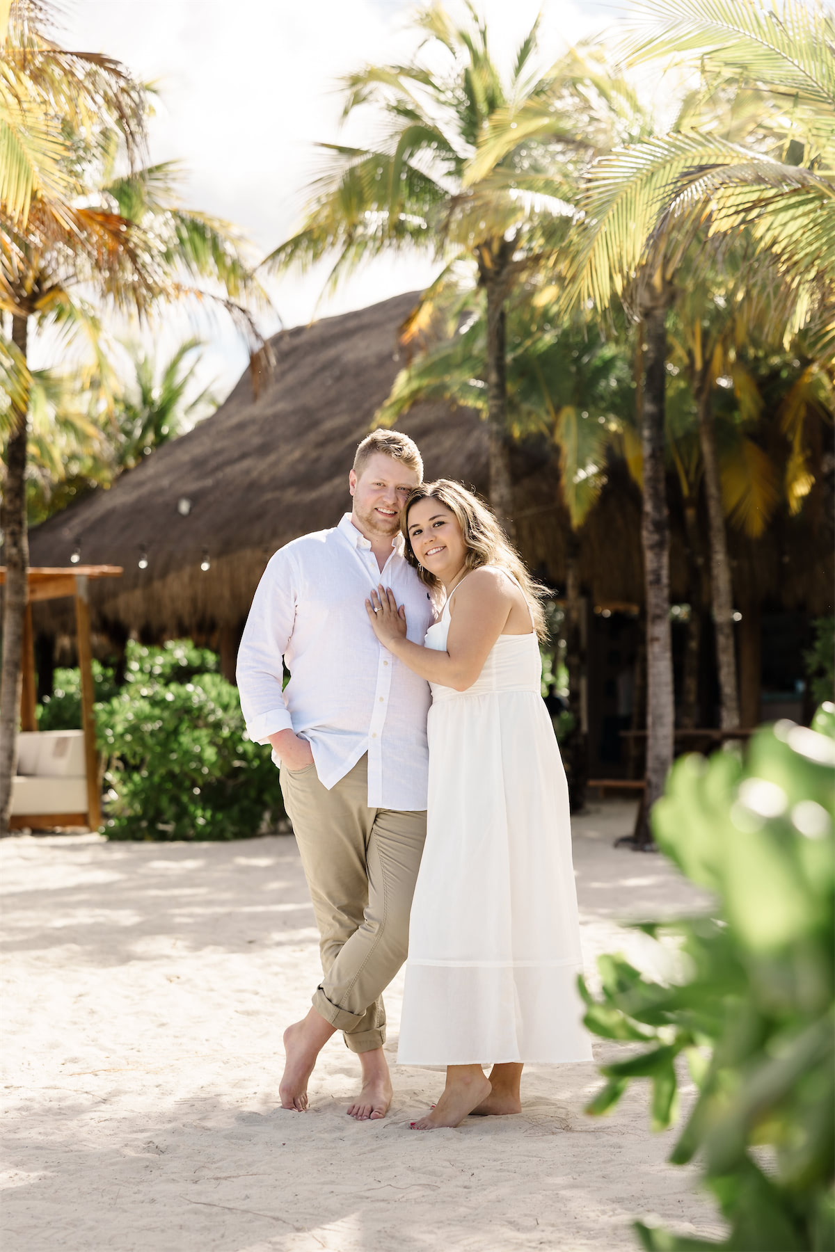 A man and woman in summer outfits posing together on the sandy beach during their Chankanaab Park engagement in Cozumel.