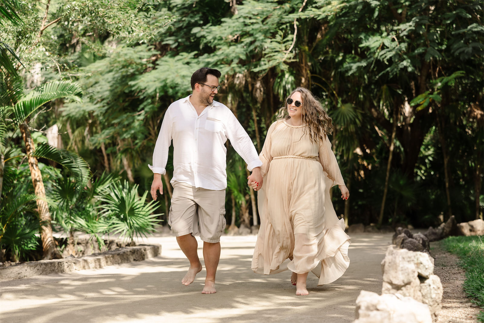 A couple holding hands and walking along a tropical jungle path during their vacation in Cozumel.